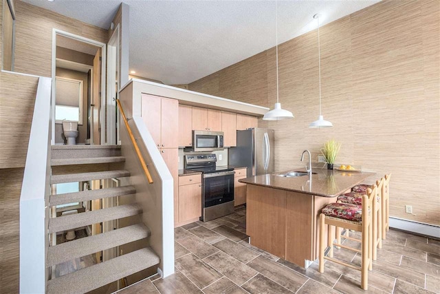 302 Quaintance Ave, Petoskey, MI 49770 - kitchen featuring stainless steel appliances, a sink, light brown cabinetry, and a kitchen bar