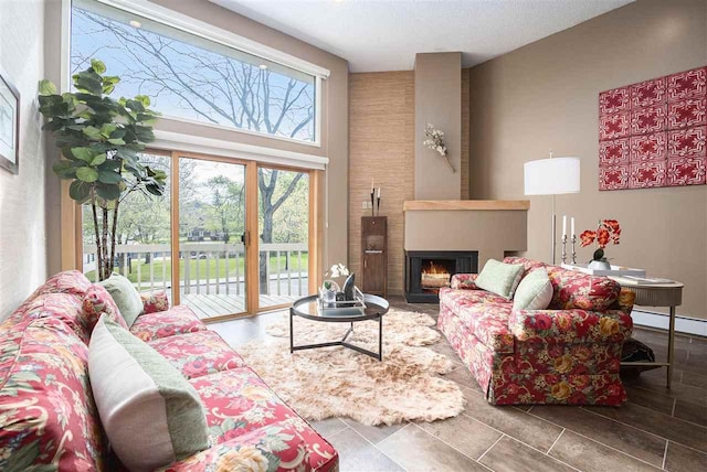 302 Quaintance Ave, Petoskey, MI 49770 - living room featuring a large fireplace, a towering ceiling, and a baseboard radiator