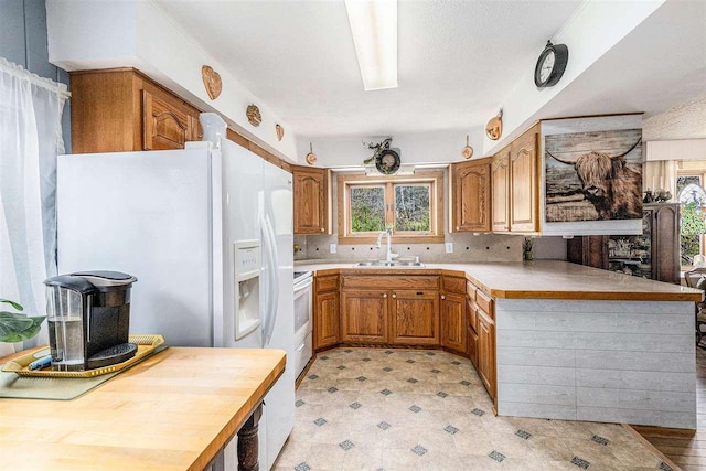 6073 Rocky Beach Ave, Charlevoix, MI 49720 - kitchen with a peninsula, a sink, brown cabinets, light countertops, and white range with electric cooktop