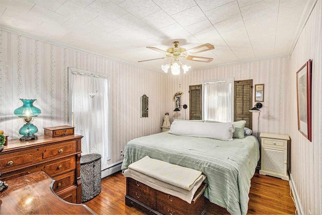 6073 Rocky Beach Ave, Charlevoix, MI 49720 - bedroom featuring hardwood / wood-style floors, wallpapered walls, ornamental molding, a baseboard radiator, and ceiling fan
