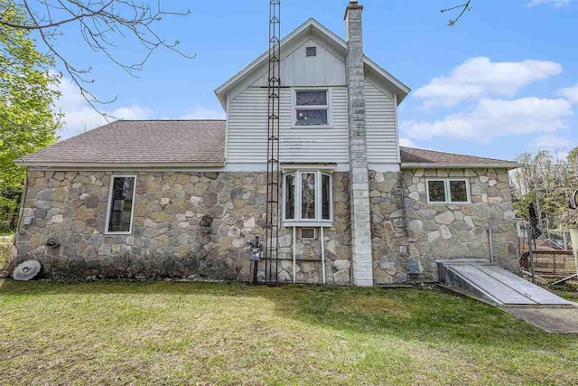 6073 Rocky Beach Ave, Charlevoix, MI 49720 - back of house with stone siding, a chimney, a yard, and a shingled roof