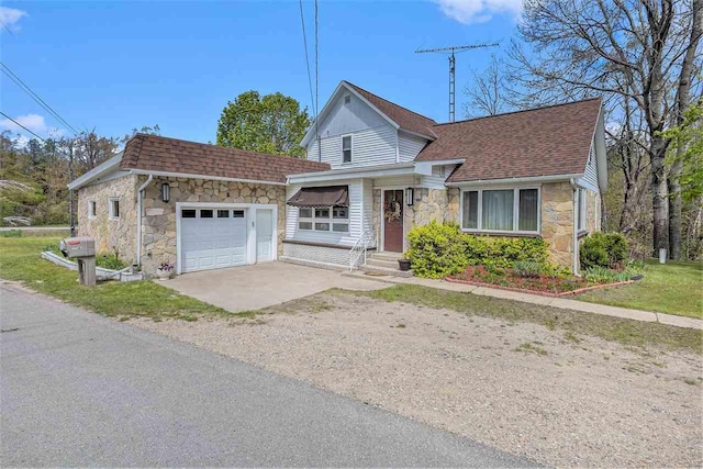 6073 Rocky Beach Ave, Charlevoix, MI 49720 - view of front of home with stone siding, driveway, roof with shingles, and an attached garage