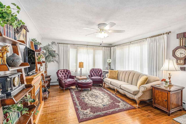 6073 Rocky Beach Ave, Charlevoix, MI 49720 - living area featuring a textured ceiling, plenty of natural light, ceiling fan, light wood-style flooring, and a baseboard radiator