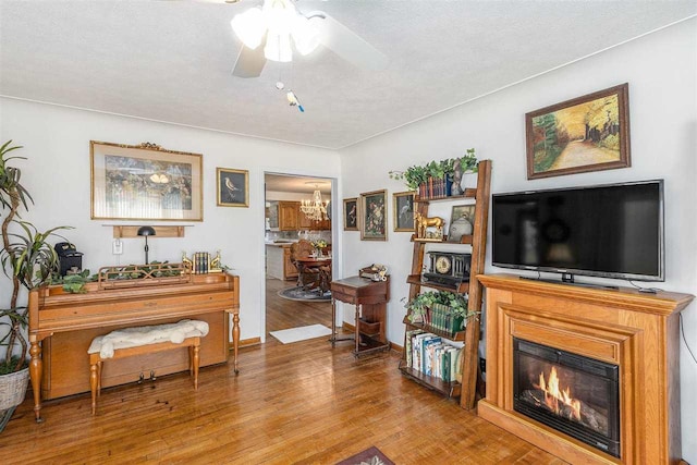 6073 Rocky Beach Ave, Charlevoix, MI 49720 - living area with a ceiling fan, wood finished floors, a glass covered fireplace, a chandelier, and a textured ceiling