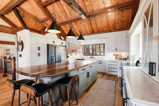 2149 Old Horton Bay Rd, Boyne City, MI 49712 - kitchen with high end appliances, wood ceiling with exposed beams, butcher block countertops, light wood-style flooring, and white cabinets