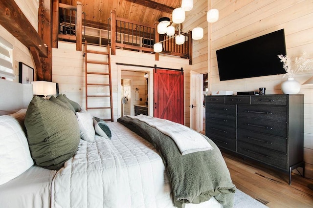 2149 Old Horton Bay Rd, Boyne City, MI 49712 - bedroom with wood walls, a barn door, wood finished floors, wood ceiling with exposed beams, and a chandelier