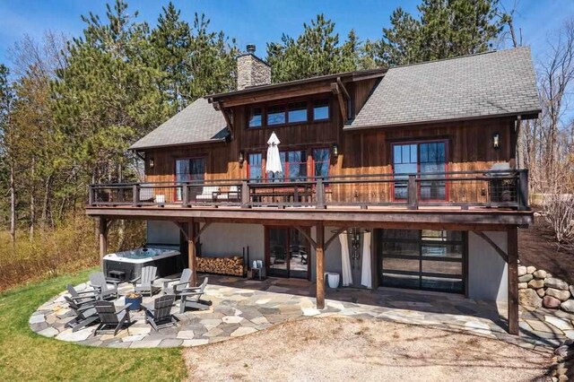 2149 Old Horton Bay Rd, Boyne City, MI 49712 - rear view of property with a chimney, a patio area, a deck, a hot tub, and a shingled roof