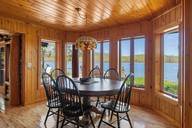 10819 Pioneer Trl, Boyne Falls, MI 49713 - dining room with a water view, wood walls, plenty of natural light, light wood-type flooring, and baseboards