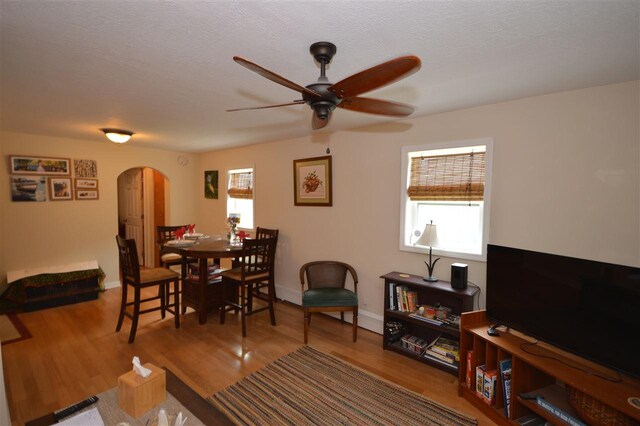 413 E Main St, Boyne City, MI 49712 - living area with arched walkways, a ceiling fan, wood finished floors, baseboards, and a textured ceiling
