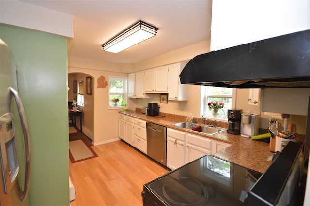413 E Main St, Boyne City, MI 49712 - kitchen featuring appliances with stainless steel finishes, a sink, ventilation hood, light wood-style floors, and white cabinets