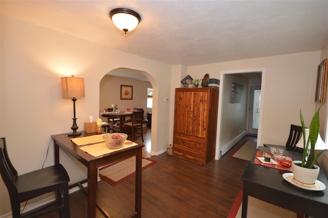 413 E Main St, Boyne City, MI 49712 - home office with a baseboard heating unit, arched walkways, dark wood-type flooring, and baseboards