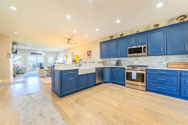 6040 Pine Lake Club Dr Unit 24, Charlevoix, MI 49720 - kitchen with appliances with stainless steel finishes, blue cabinets, a peninsula, ceiling fan, and light countertops