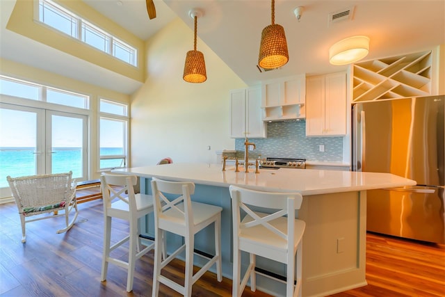 301 Michigan Ave Unit 13, Charlevoix, MI 49720 - kitchen with stainless steel appliances, exhaust hood, decorative backsplash, wood finished floors, and pendant lighting