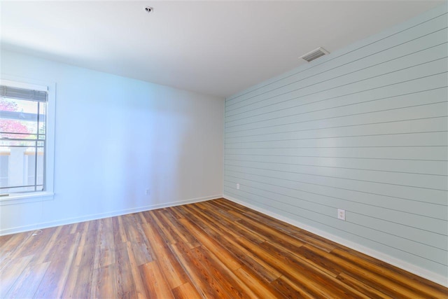 301 Michigan Ave Unit 13, Charlevoix, MI 49720 - empty room with wood finished floors, fire sprinkler in ceiling, wood walls, and baseboards