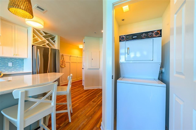 301 Michigan Ave Unit 13, Charlevoix, MI 49720 - kitchen with stacked washer / dryer, freestanding refrigerator, dark wood-style flooring, white cabinetry, and light countertops