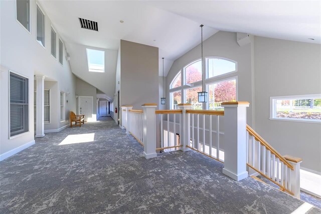 301 Michigan Ave Unit 13, Charlevoix, MI 49720 - corridor featuring carpet flooring, high vaulted ceiling, an upstairs landing, healthy amount of natural light, and baseboards