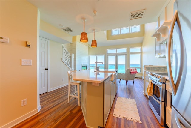 301 Michigan Ave Unit 13, Charlevoix, MI 49720 - kitchen with stainless steel appliances, dark wood-type flooring, light countertops, an island with sink, and decorative light fixtures