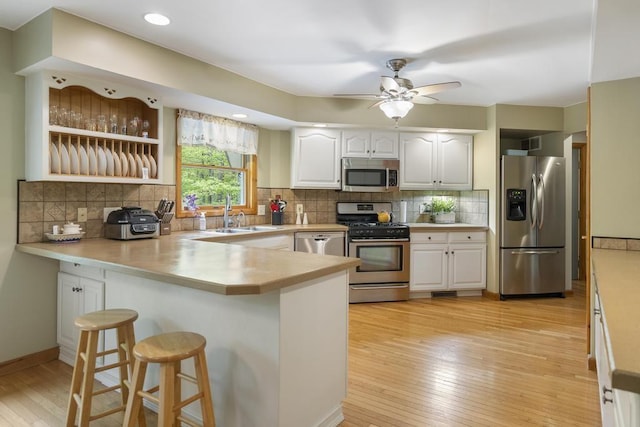 4545 Lintlong Rd, Petoskey, MI 49770 - kitchen featuring stainless steel appliances, a peninsula, a sink, light wood-style flooring, and a breakfast bar area