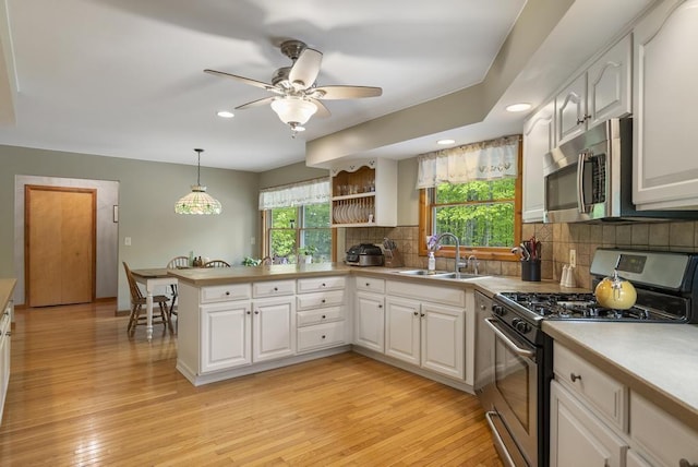 4545 Lintlong Rd, Petoskey, MI 49770 - kitchen featuring appliances with stainless steel finishes, a sink, a peninsula, white cabinets, and decorative backsplash