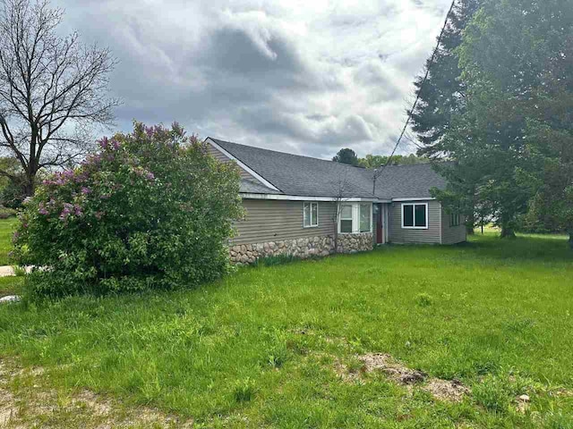 2378 E Old State Rd, East Jordan, MI 49727 - back of property featuring a shingled roof, a lawn, and stone siding