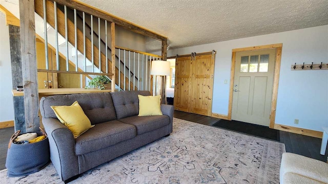 15718 N Blueberry Ln, Paradise, MI 49768 - living area with wood finished floors, stairway, baseboards, a barn door, and a textured ceiling