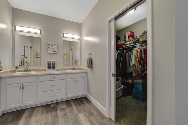 7101 Partridge Pl, Gaylord, MI 49735 - full bathroom with wood finished floors, double vanity, a walk in closet, and baseboards