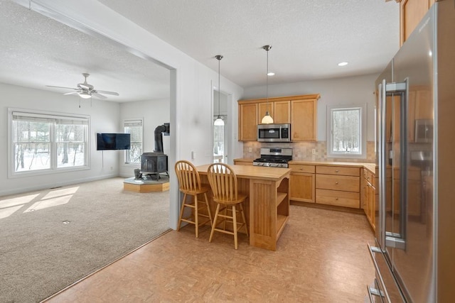 2508 Terpening Rd, Harbor Springs, MI 49740 - kitchen with stainless steel appliances, a wood stove, a textured ceiling, open floor plan, and backsplash