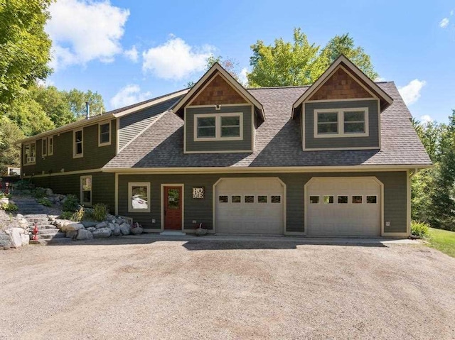 03675 Bc/Ej Rd, East Jordan, MI 49727 - view of front facade featuring a garage, a shingled roof, and driveway