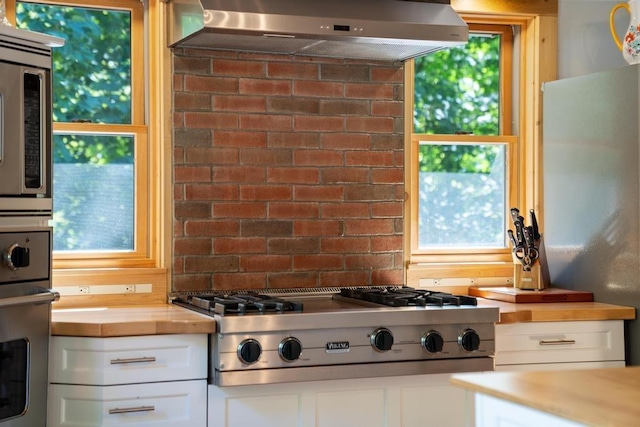03675 Bc/Ej Rd, East Jordan, MI 49727 - kitchen featuring exhaust hood, appliances with stainless steel finishes, white cabinets, and plenty of natural light