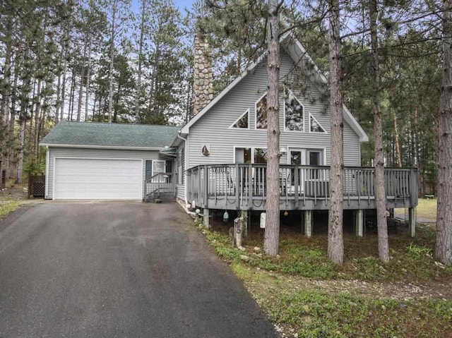 4460 E Fontenoy St, Boyne City, MI 49712 - rustic home with driveway, an attached garage, a deck, and a chimney