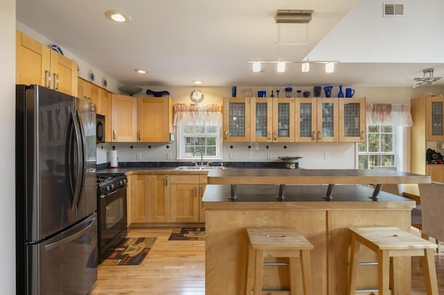 4460 E Fontenoy St, Boyne City, MI 49712 - kitchen with black appliances, a sink, dark countertops, light wood-style floors, and a breakfast bar