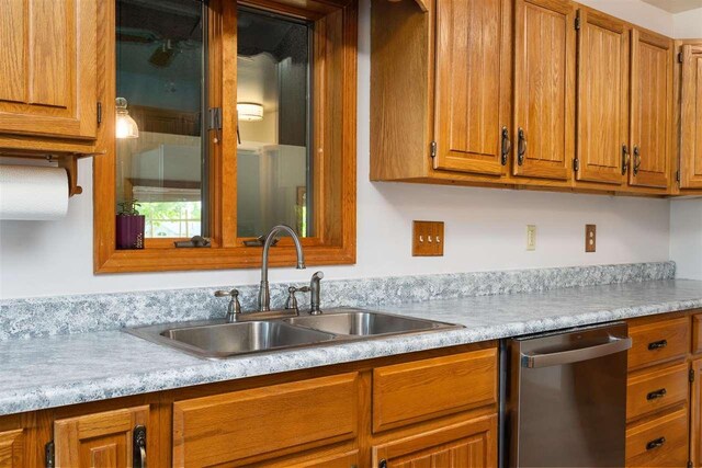 10370 Boyne City Rd, Charlevoix, MI 49720 - kitchen with stainless steel dishwasher, a sink, light countertops, and brown cabinetry