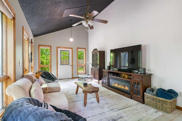 10370 Boyne City Rd, Charlevoix, MI 49720 - living area featuring high vaulted ceiling, tile patterned flooring, ceiling fan, and a glass covered fireplace