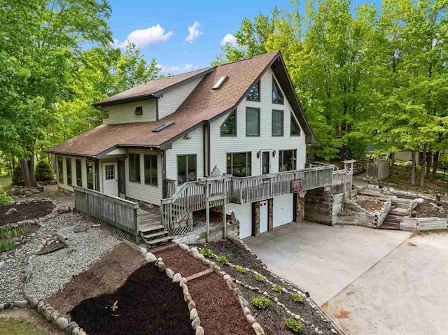 10370 Boyne City Rd, Charlevoix, MI 49720 - back of house featuring roof with shingles, an attached garage, driveway, and a deck