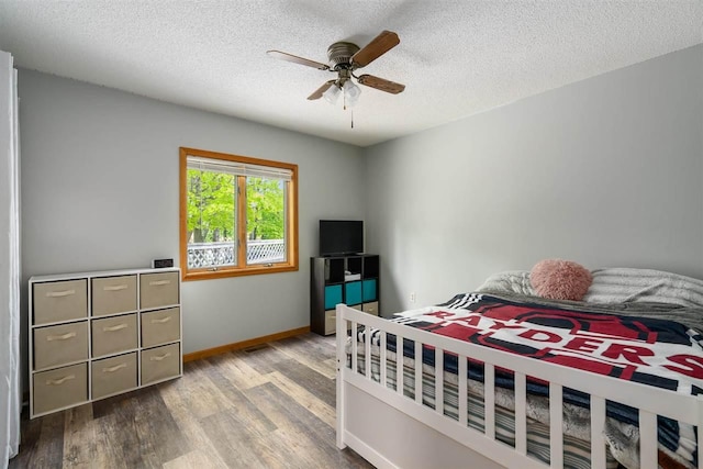 10370 Boyne City Rd, Charlevoix, MI 49720 - bedroom featuring wood finished floors, a textured ceiling, baseboards, and ceiling fan