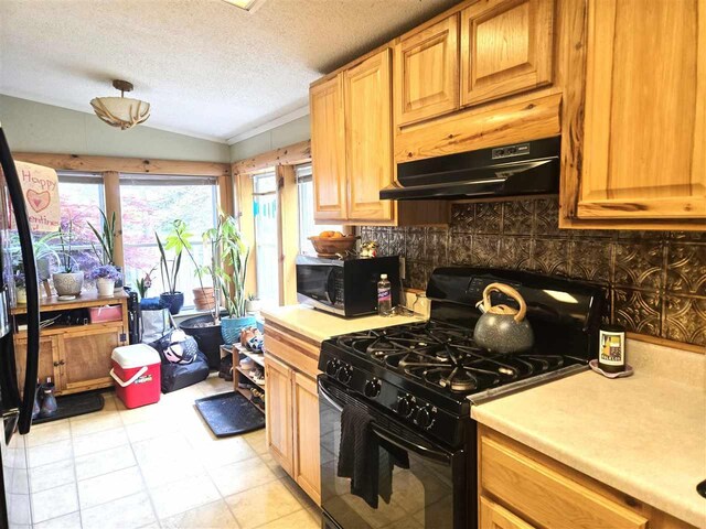 05671 N M-66 N, Charlevoix, MI 49720 - kitchen featuring black appliances, under cabinet range hood, vaulted ceiling, light countertops, and decorative backsplash