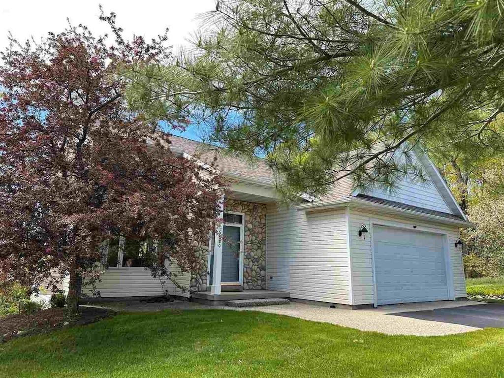 6680 Hillside Dr, Harbor Springs, MI 49740 - view of property hidden behind natural elements with driveway, a front yard, and an attached garage