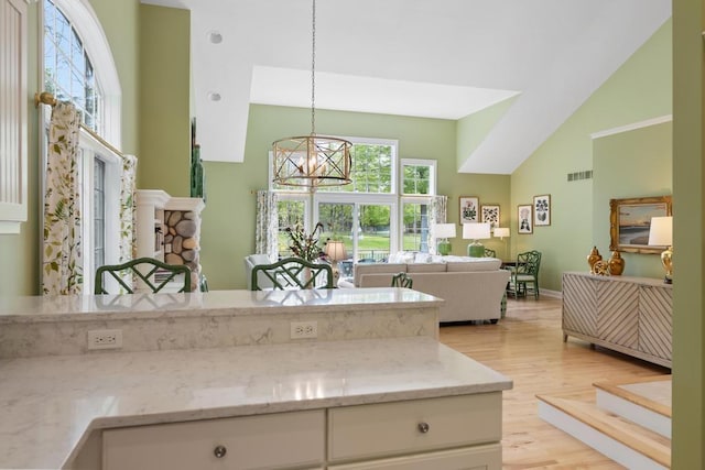 6707 Cottage Ct Unit 40, Bay Harbor, MI 49770 - kitchen with high vaulted ceiling, light wood-type flooring, white cabinetry, light stone countertops, and pendant lighting