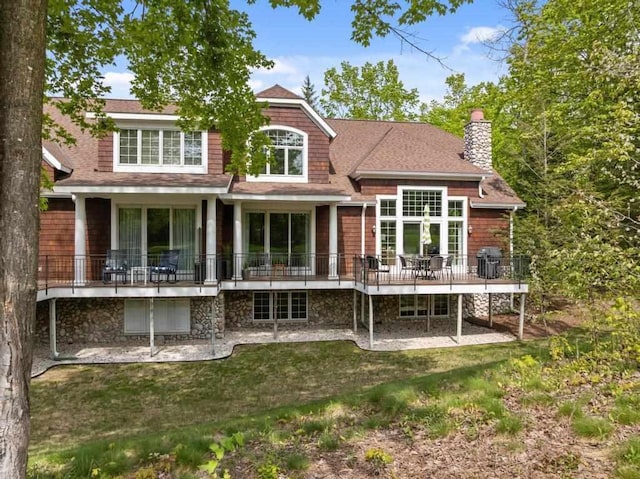 6707 Cottage Ct Unit 40, Bay Harbor, MI 49770 - back of property featuring a chimney, a wooden deck, a lawn, and a shingled roof