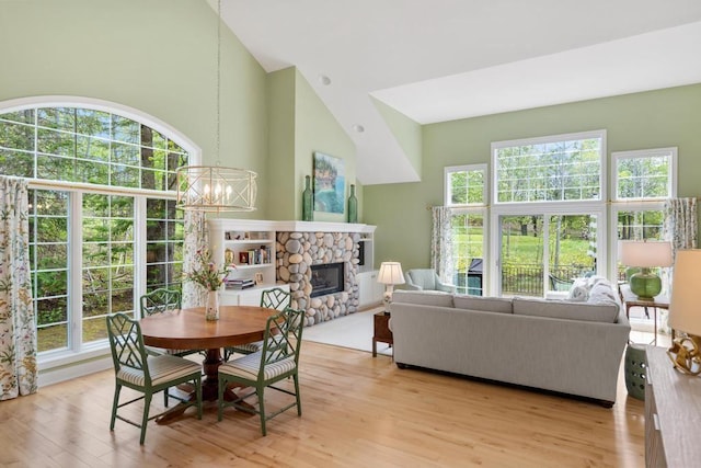6707 Cottage Ct Unit 40, Bay Harbor, MI 49770 - dining room with high vaulted ceiling, light wood-type flooring, healthy amount of natural light, a fireplace, and a chandelier