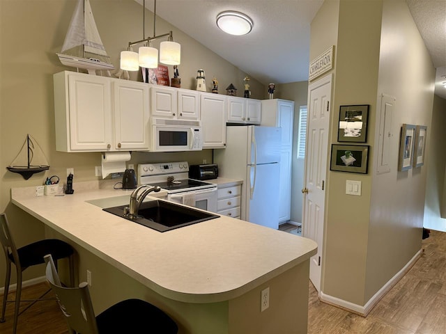 13435 Creekside Ln Unit 4, Charlevoix, MI 49720 - kitchen featuring white appliances, a kitchen bar, light countertops, a peninsula, and lofted ceiling