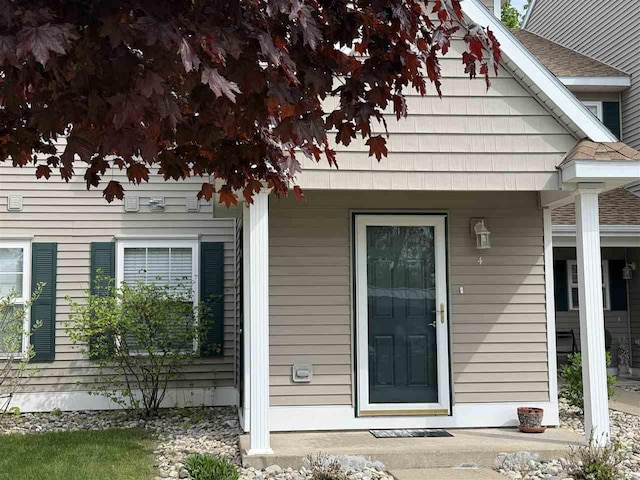 13435 Creekside Ln Unit 4, Charlevoix, MI 49720 - view of exterior entry featuring roof with shingles and a porch