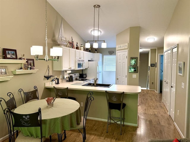 13435 Creekside Ln Unit 4, Charlevoix, MI 49720 - kitchen with white appliances, a peninsula, light countertops, and a breakfast bar area