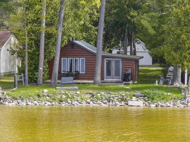 21677 Bluffs Hwy, Onaway, MI 49765 - rear view of house with faux log siding, a water view, and an outbuilding