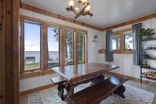 21677 Bluffs Hwy, Onaway, MI 49765 - dining space with a chandelier, wood-type flooring, and wooden walls