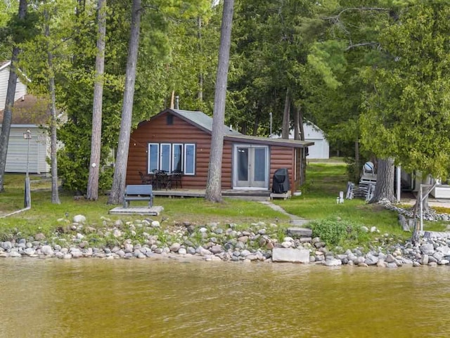 21677 Bluffs Hwy, Onaway, MI 49765 - back of property with faux log siding, a water view, an outdoor structure, and french doors