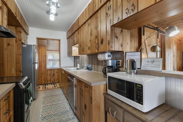 21677 Bluffs Hwy, Onaway, MI 49765 - kitchen with stainless steel appliances, a sink, brown cabinets, light countertops, and wood walls