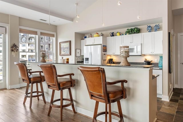 824 Vista Dr Unit 64, Bay Harbor, MI 49770 - kitchen featuring white appliances, dark countertops, a breakfast bar area, and baseboards