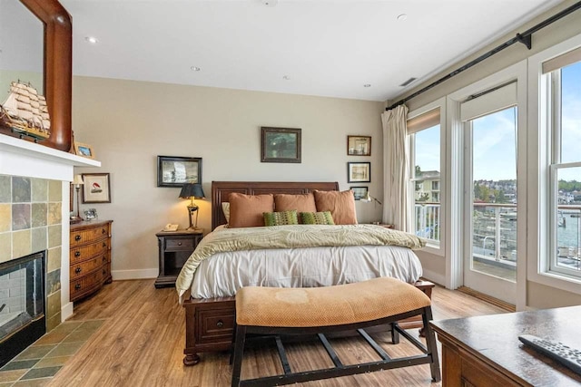 824 Vista Dr Unit 64, Bay Harbor, MI 49770 - bedroom with access to outside, light wood-type flooring, a tile fireplace, baseboards, and recessed lighting