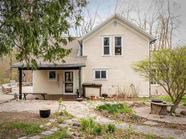 7671 Hoyt Rd, Harbor Springs, MI 49740 - back of property with an outdoor fire pit, a patio area, and a shingled roof